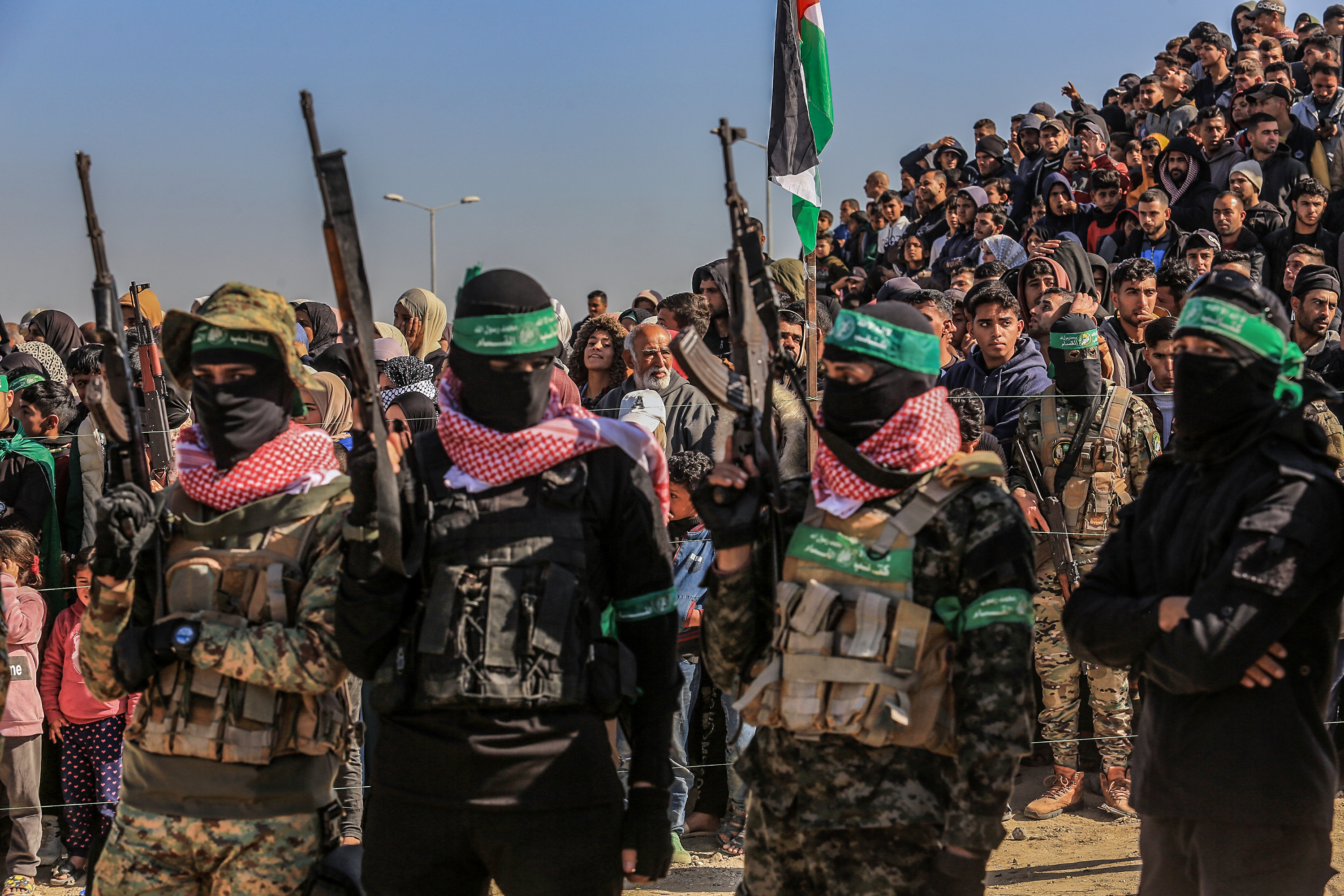 Hamas members and Palestinians watch as Israeli hostages are handed over to Red Cross representatives in the southern Gaza Strip city of Khan Younis.