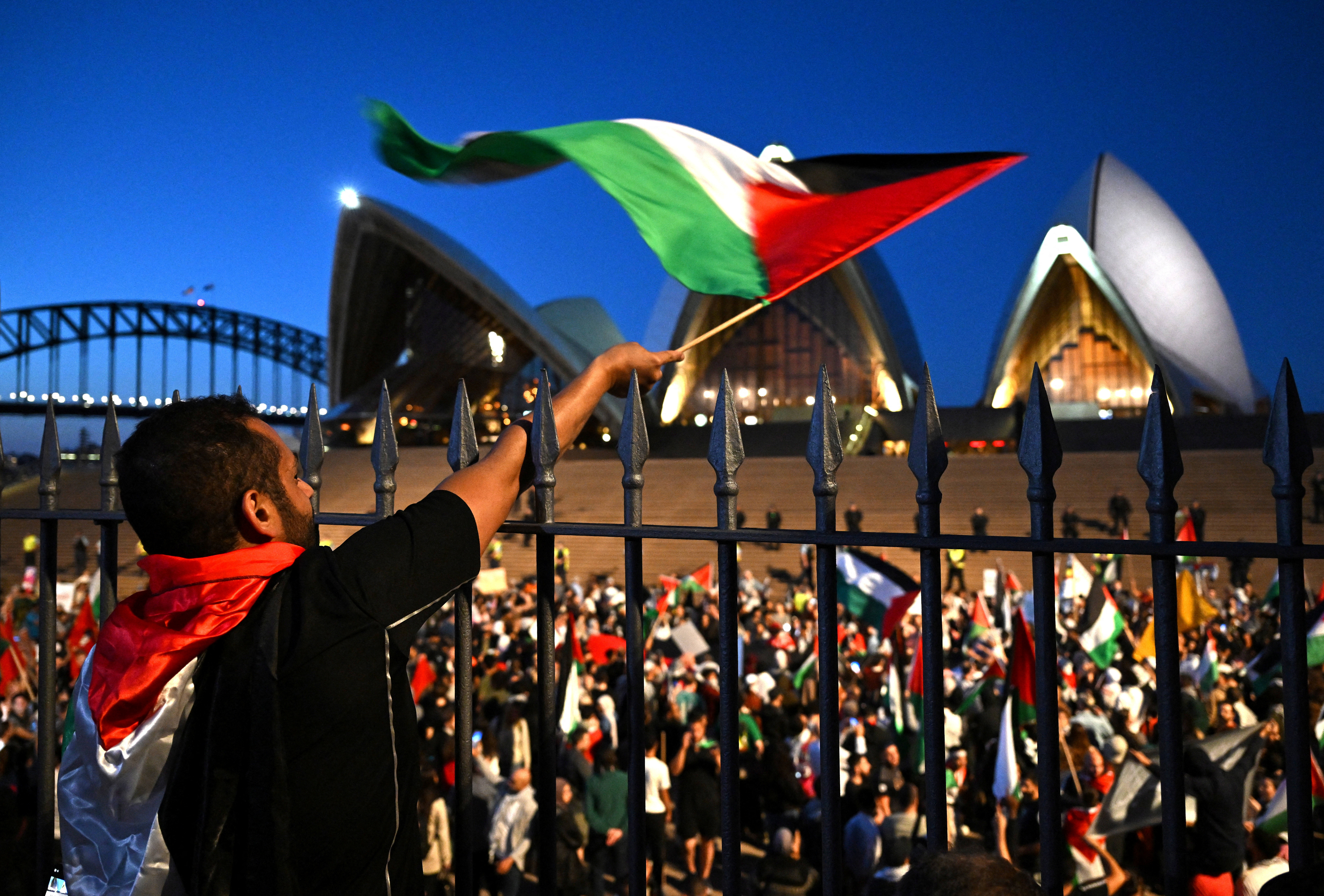 A demonstrator waves a flag during a pro-Palestinian rally near the Sydney Opera House in Sydney, Australia, October 9, 2023. AAP/Dean Lewins/via REUTERS