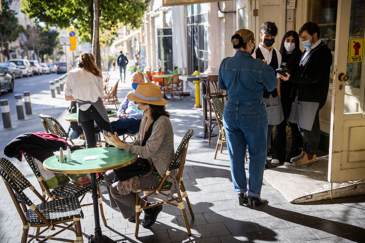 Customers sit at the Kadosh Cafe Patisserie in Jerusalem after it was reopened on March 7, 2021. Photo by Yonatan Sindel/Flash90