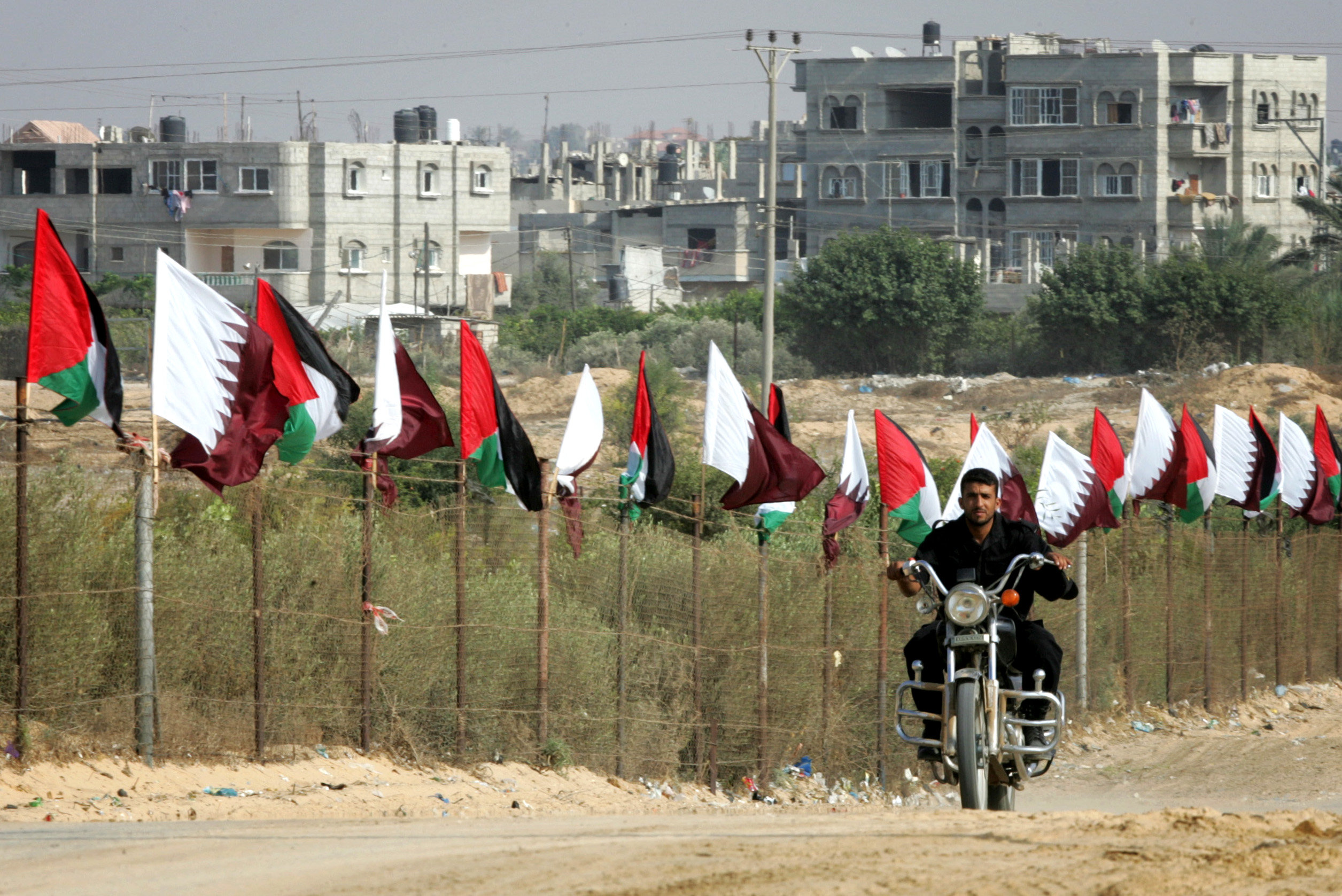 Member of Hamas security forces rides a motorcycle next to Palestinian and Qatar flags during preparations for the celebratory reception of Qatar's Emir Sheik Hamad bin Khalifa al-Thani, in Khan Younis in the southern Gaza Strip on October 22, 2012. The emir of pro-Western Qatar will become the first head of state to enter the blockaded Gaza Strip on Tuesday, in a high-profile visit breaking the isolation of the Iranian-backed Islamist movement Hamas that seized power in 2007. Photo by Abed Rahim Khatib / Flash 90